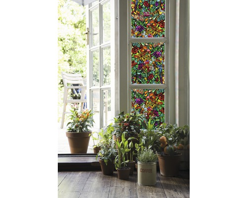 Dekorfolie mit Pflanzenmuster auf Fenstern, umgeben von Topfpflanzen und einer offenen Tür