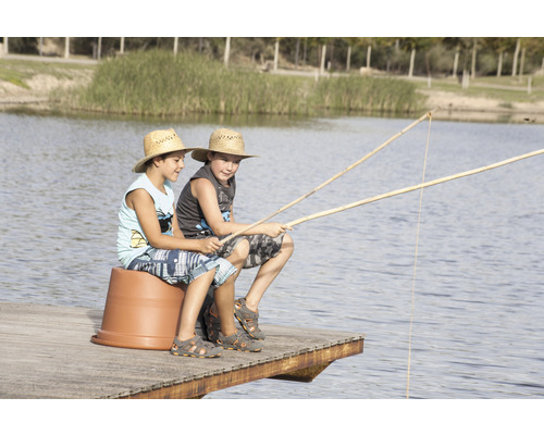 Zwei Jungen sitzen mit Angelruten auf einem Steg an einem See.