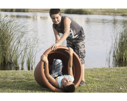 Zwei Jungen spielen mit einem großen Pflanzgefäß im Freien.