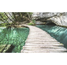Holzsteg über türkisfarbenen See zu einer Höhle