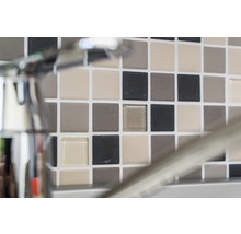 Mosaikfliesenwand mit verschiedenen Farbtönen hinter einem Wasserhahn