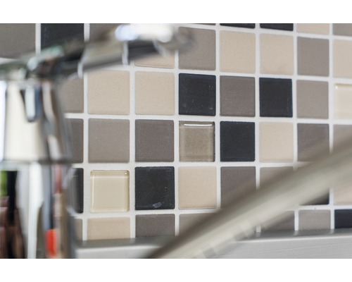 Mosaikfliesenwand mit verschiedenen Farbtönen hinter einem Wasserhahn