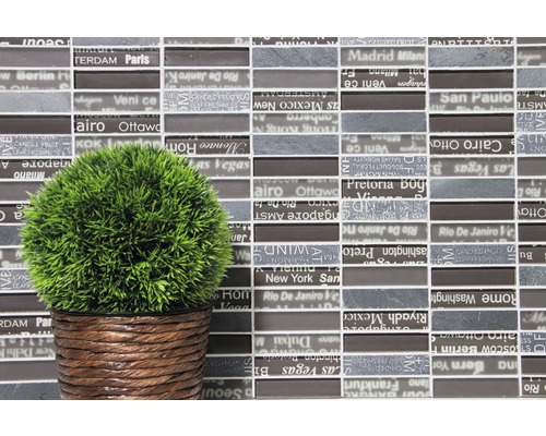 Dekorative Mosaikfliesen mit Stadtnamen und eine Kunstpflanze in einem geflochtenen Topf