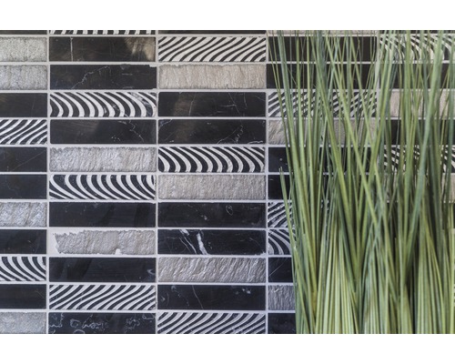 Dekorative Mosaikfliesen in Schwarz, Weiß und Grau neben Ziergras