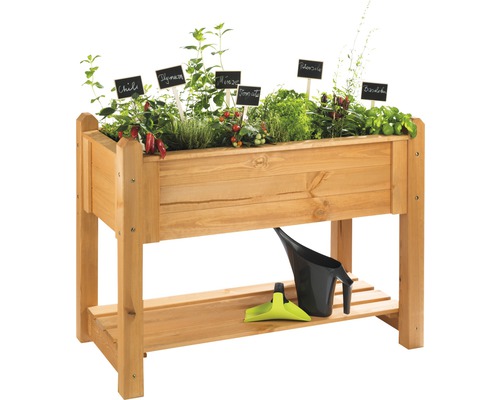 Hochbeet aus Holz mit Kräutern und Gemüse sowie Gießkanne und Schaufel