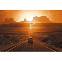 Eine Straße führt durch eine weite Landschaft mit Felsformationen und einem einzelnen Auto.