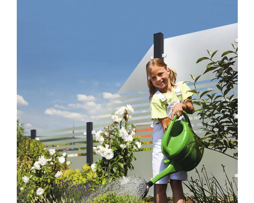 Mädchen gießt Gartenpflanzen mit einer Gießkanne