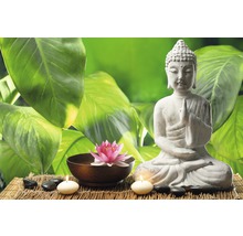 Dekorative Buddhafigur neben Lotusblume und Kerzen auf Bambusmatte