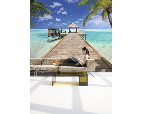 Wandbild mit tropischem Strandmotiv und Frau auf Sofa