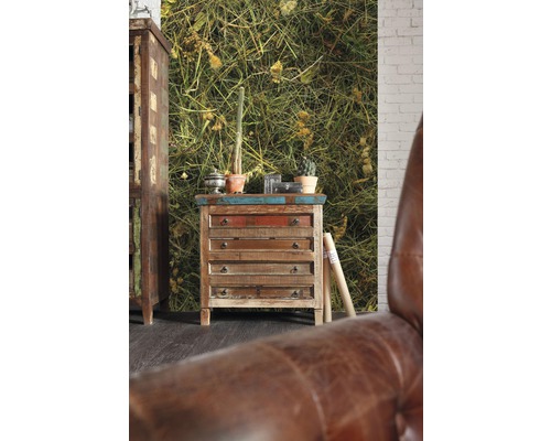 Szene mit Kommode aus Holz und Fototapete mit Pflanzenmotiv.