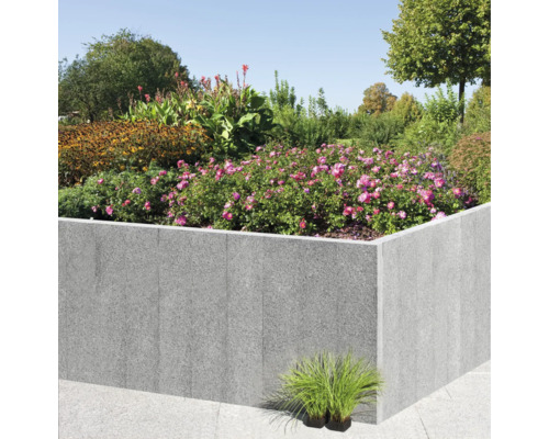 Hochbeet aus Stein mit blühenden Pflanzen und Sträuchern im Garten