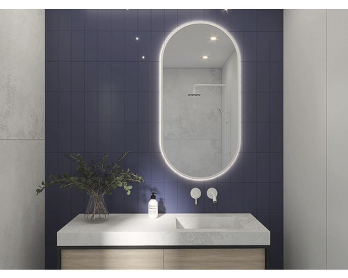 Badezimmer mit Waschtisch, Spiegel mit Beleuchtung und blauer Fliesenwand