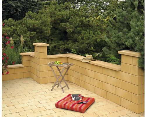 Terrasse mit Mauern aus Betonsteinen, Tisch, Kissen und Hut