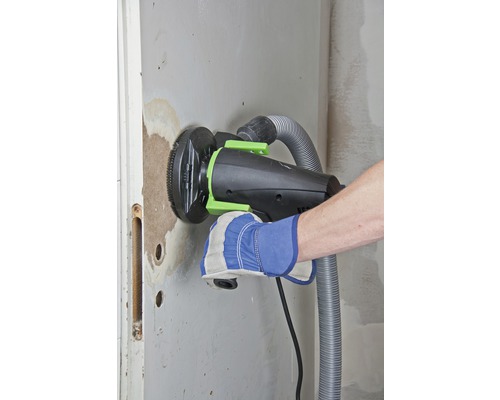 Handwerker schleift Wand mit Mauernutfräse mit Staubabsaugung