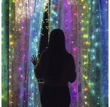 Frau steht vor Fenster mit Twinkly Lichterkette
