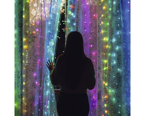 Frau steht vor Fenster mit Twinkly Lichterkette