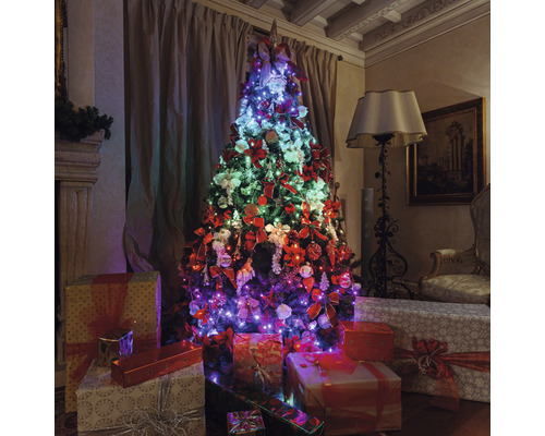 Geschmückter Weihnachtsbaum mit Geschenken in einem Wohnzimmer.