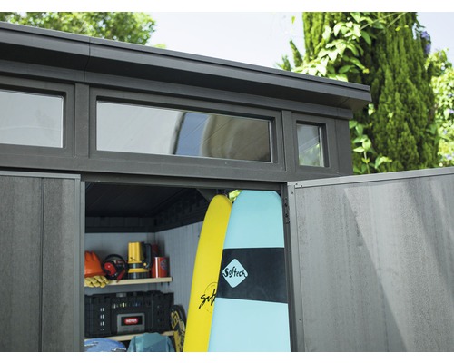 Gartenschuppen mit Fenstern und geöffneten Türen, gefüllt mit Surfbrettern und Werkzeugen.