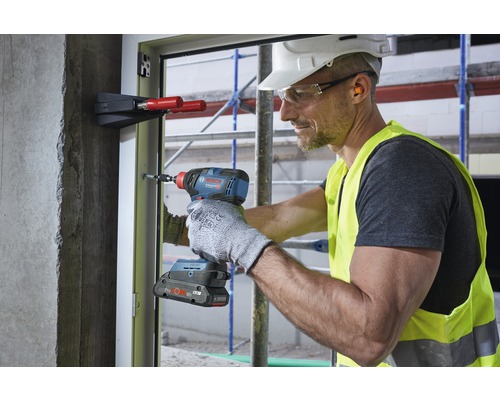 Handwerker verwendet einen Akku-Schlagschrauber an einem Fensterrahmen auf einer Baustelle.