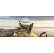 Dekorative Glaskugel auf einem Baumstumpf am Strand