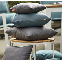Stapel dekorativer Kissen auf einem Gartentisch.