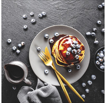 Teller mit Pfannkuchen, Schokoladensoße und Blaubeeren mit Messer und Gabel