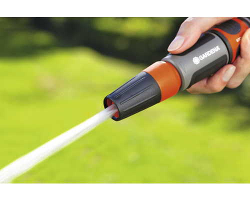 Eine Hand hält eine Gartenspritze der Marke Gardena, aus der ein Wasserstrahl kommt.