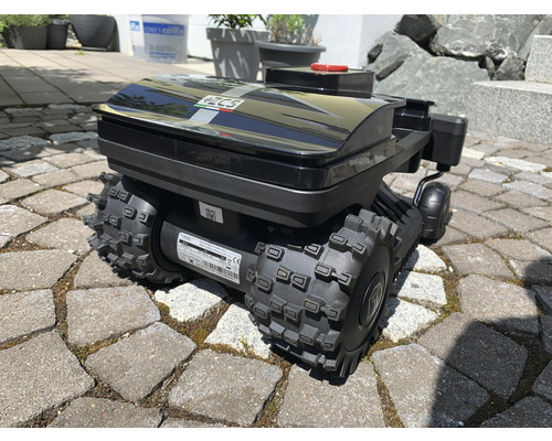 Schwarzer Rasenmähroboter mit groben Reifen auf Pflastersteinen