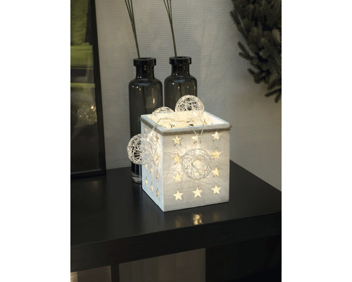 Dekorative Holzkiste mit Sternen und Lichterkette auf einem Tisch.