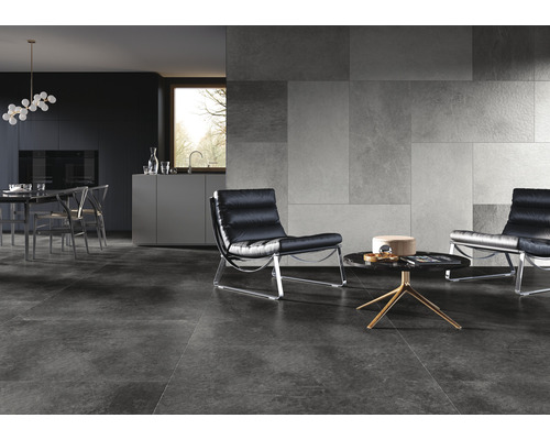 Modernes Wohnzimmer mit grauen Bodenfliesen, Wandfliesen in Steinoptik und schwarzen Ledersesseln.