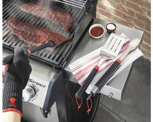 Zubereitung von Fleisch auf einem Grill mit Grillbesteck, Marinade und Grillhandschuh