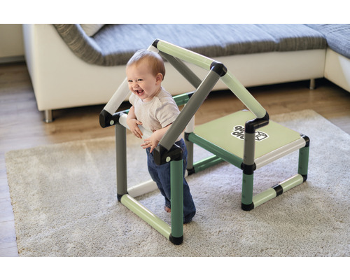 Lachendes Kind spielt mit einem modularen Kindermöbelhaus im Innenraum