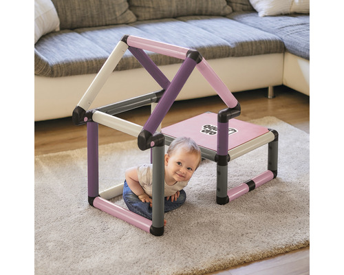 Kind spielt in einem bunten Bau-Spielhaus im Wohnzimmer.