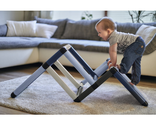 Kleinkind klettert auf einem Klettergerüst im Wohnzimmer