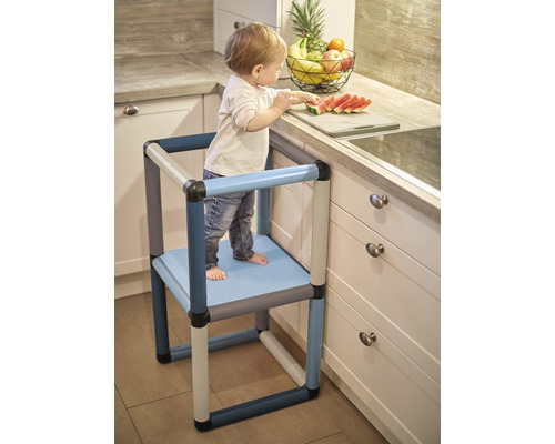 Kind auf Lernturm in der Küche beim Wassermelone schneiden