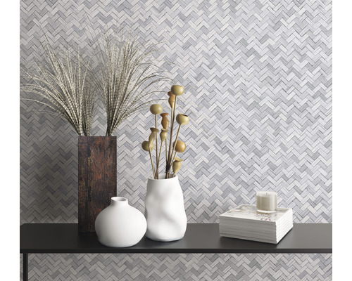 Dekorative Vasen und ein Stapel Bücher auf einem Regal vor einer Mosaikwand