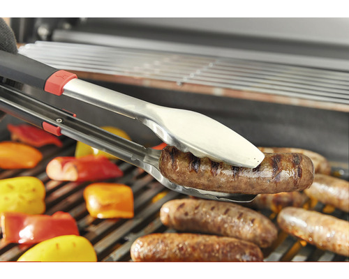 Grillzange hält Wurst über Grillrost
