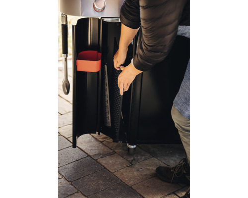 Detailansicht eines Grills mit Person, die ein Zubehörteil anbringt, um die Funktionalität des Produkts zu demonstrieren.