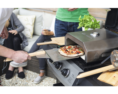 Szene mit einem Pizzaofenaufsatz auf einem Grill im Garten.