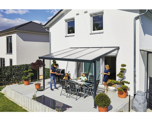 Familie grillt unter einem Terrassendach auf einer Terrasse.