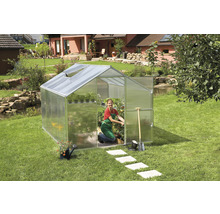 Gewächshaus im Garten mit Gärtnerin und Gartengeräten