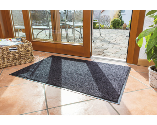 Graue Schmutzfangmatte vor einer Terrassentür auf Fliesenboden.