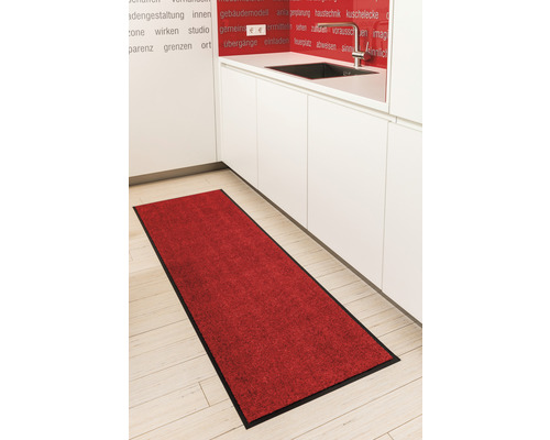 Roter Küchenläufer mit schwarzem Rand vor einem weißen Küchenblock