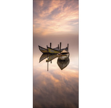 Drei kleine Boote liegen still auf dem Wasser und spiegeln sich im Wasser.