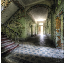 Innenansicht eines verlassenen Gebäudes mit Treppe, Flur und abblätternder Farbe.