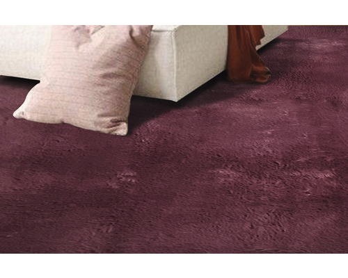 Detailansicht eines Teppichs neben einem Sofa und einem Kissen.