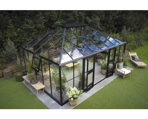 Gewächshaus mit Glaswänden und Metalrahmen im Garten.