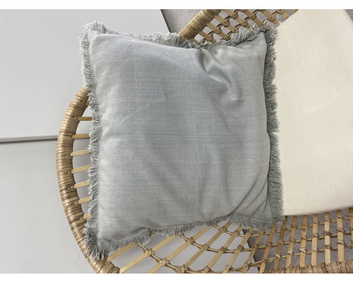 Quadratisches Kissen mit Fransen auf einem Rattansessel