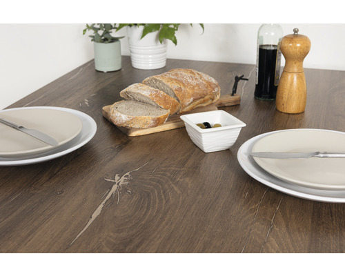 Esstisch mit Brot, Oliven, Tellern und Besteck