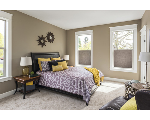 Helles Schlafzimmer mit Doppelbett, Nachttischen und Fenstern mit Rollos